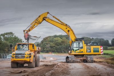 A tracked excavator loading an articulated dump truck