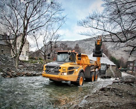 A Volvo a30g dump truck being loaded by an excavator following flooding in Glenridding.