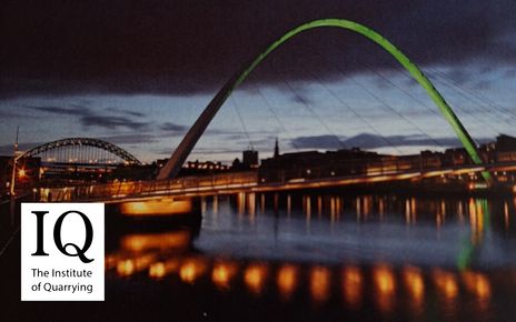 The Gateshead Millenium Bridge lit up at dusk with the Newcastle skyline and Tyne Bridge in the background